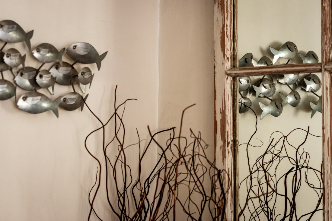 A mirror sitting next to a wall with a bunch of metal birds on it