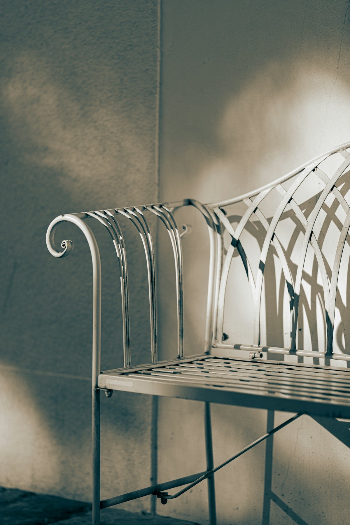 Ornate metal bench casts shadows against wall