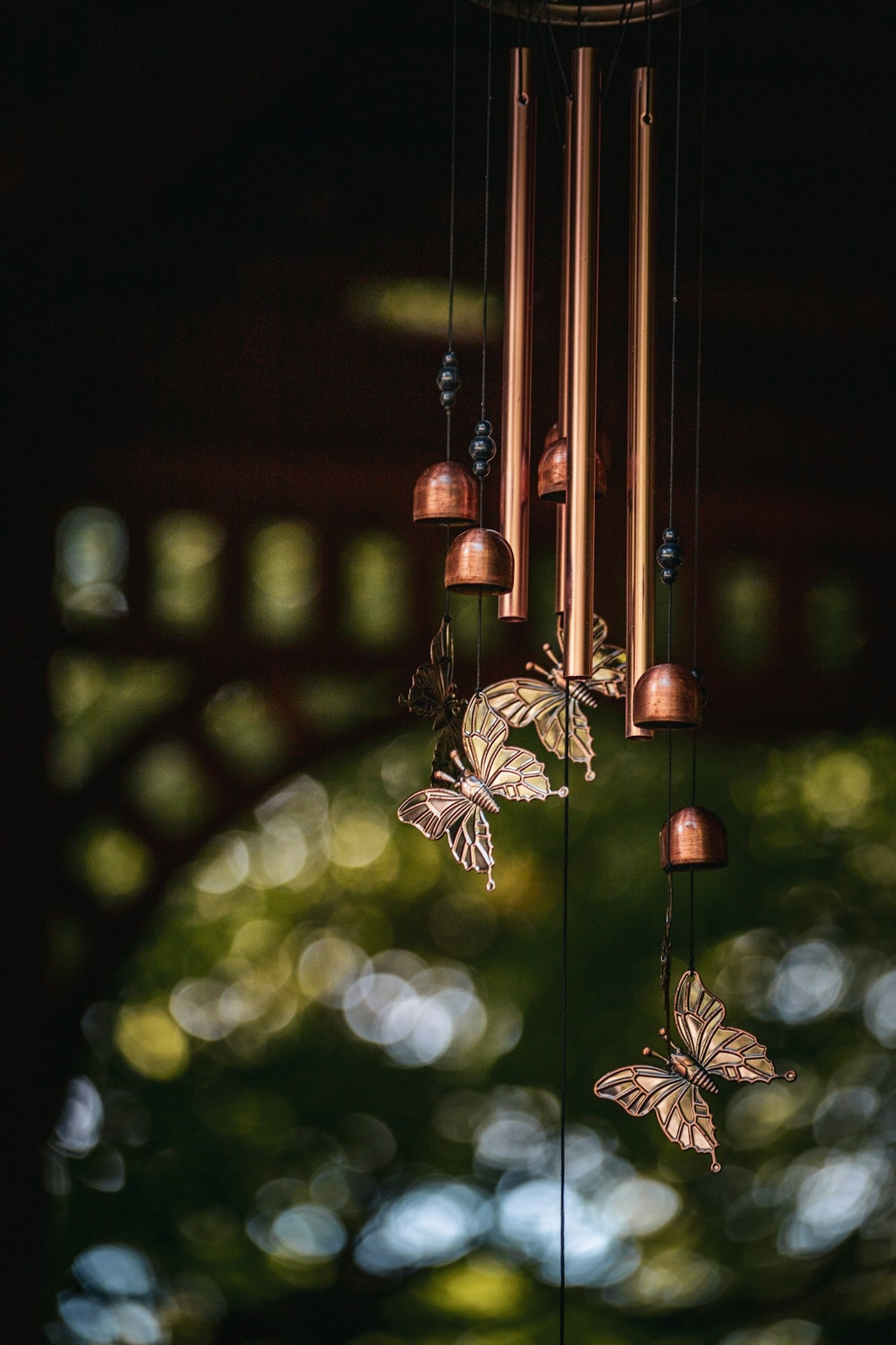 Copper wind chimes with butterfly decorations outdoors