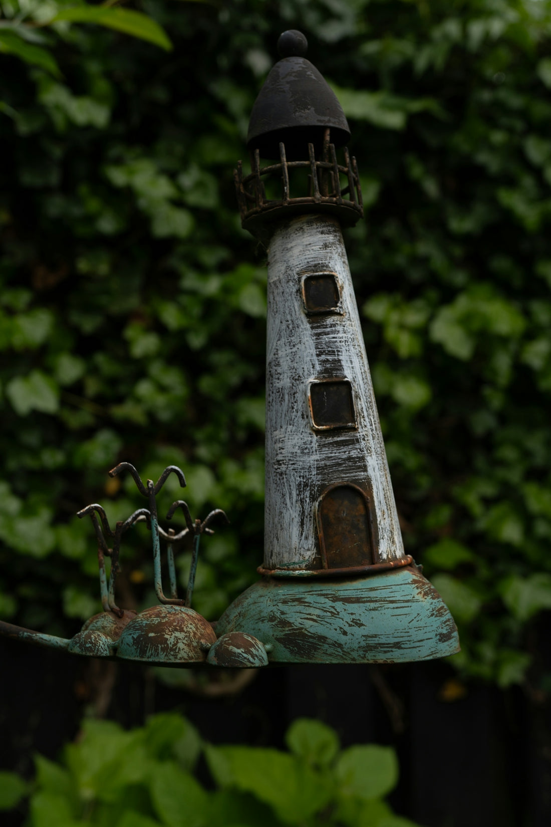 A decorative lighthouse ornament against a lush green background