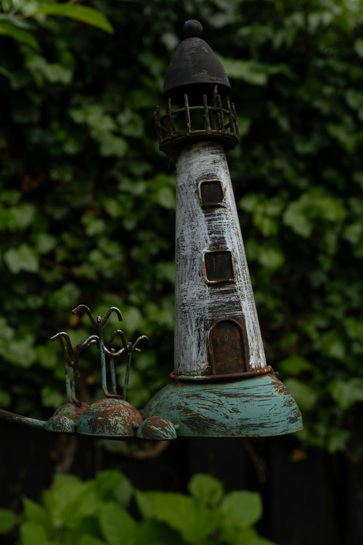 A decorative lighthouse ornament against a lush green background