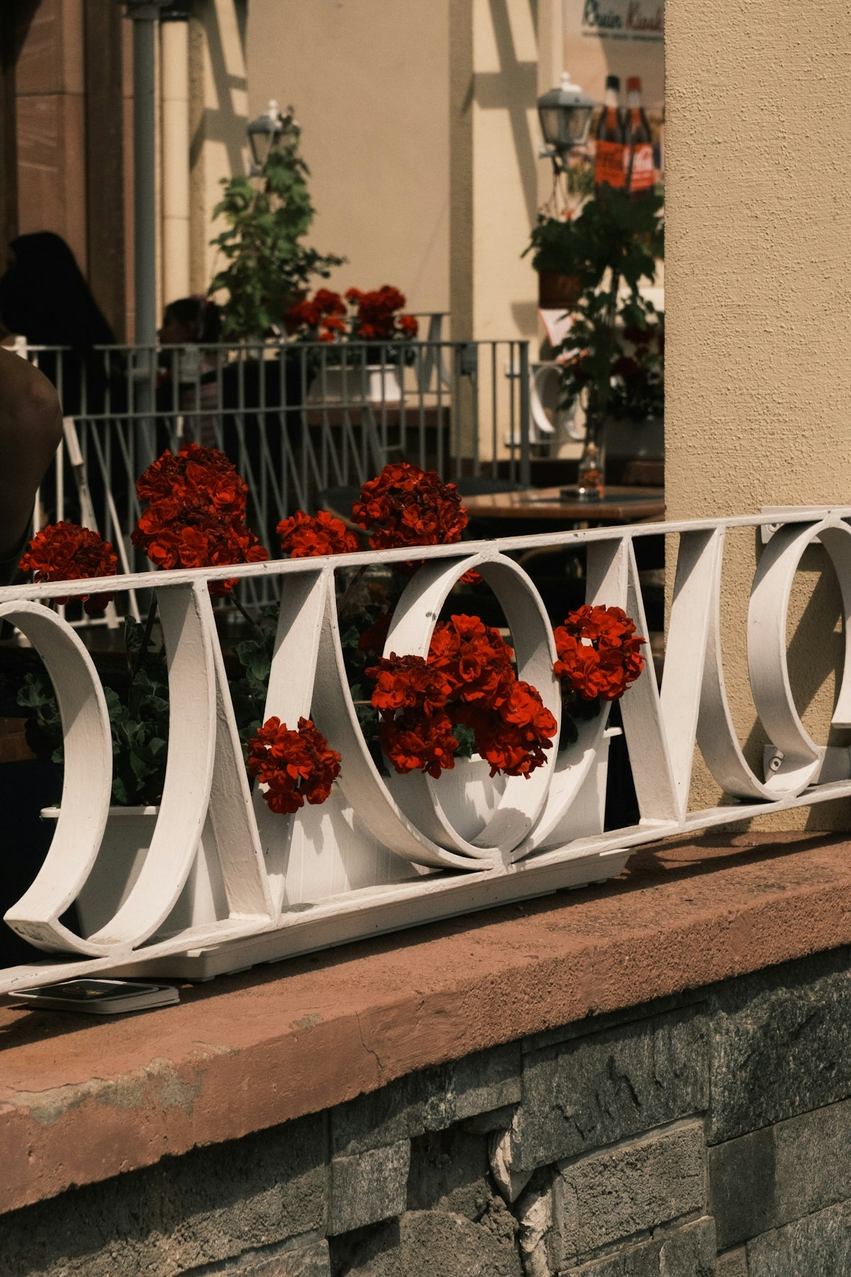 White decorative railing with red flowers outside a building