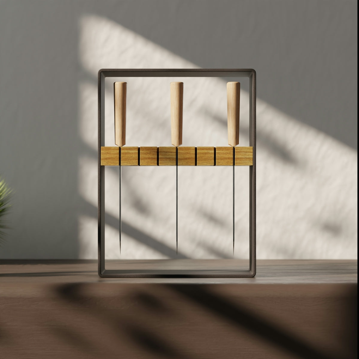 Three thin knives with wooden handles suspended in a dark metal frame on a table